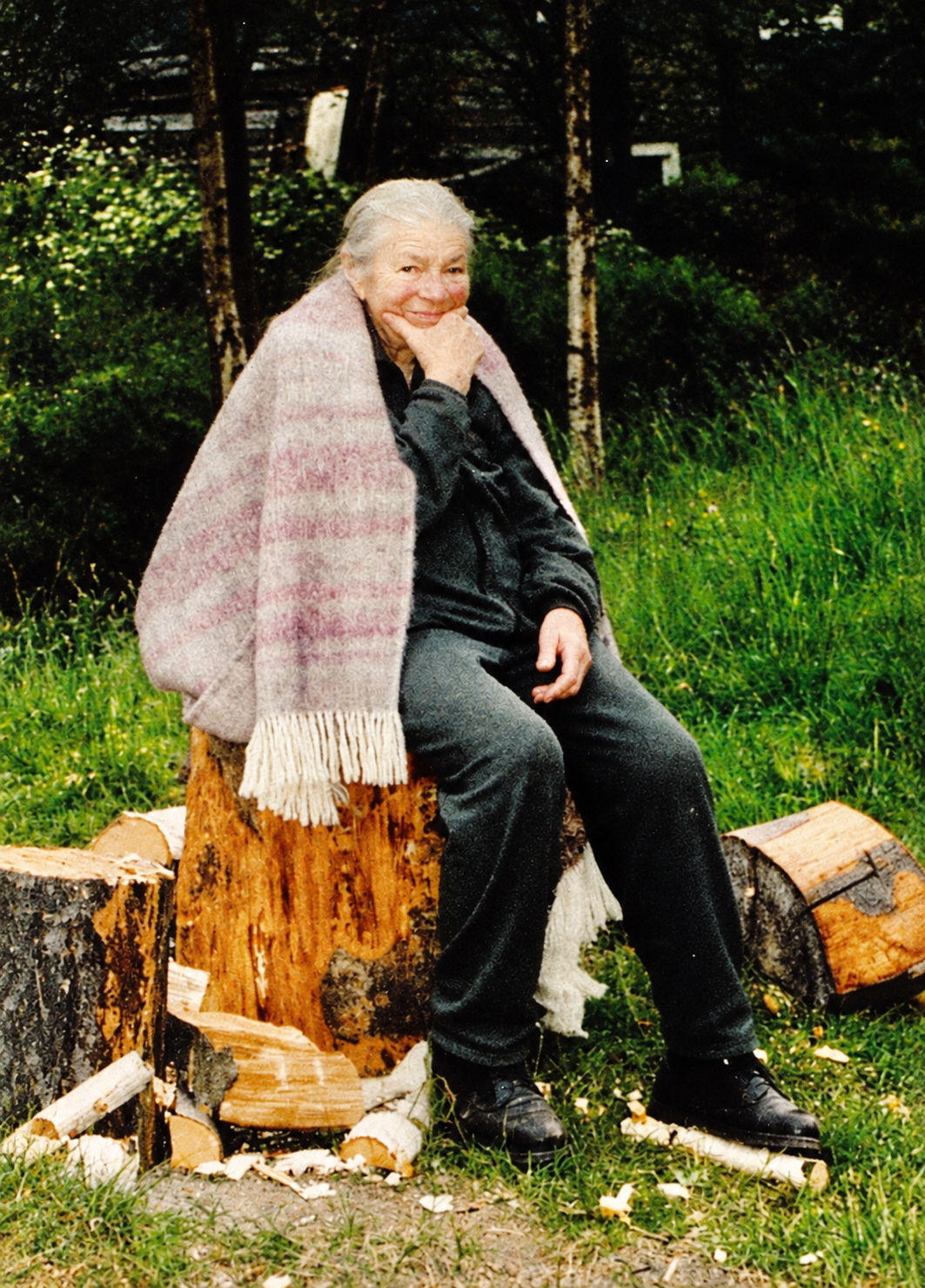 Edith Kramer seated outdoors in a wooded setting with a blanket around her shoulders